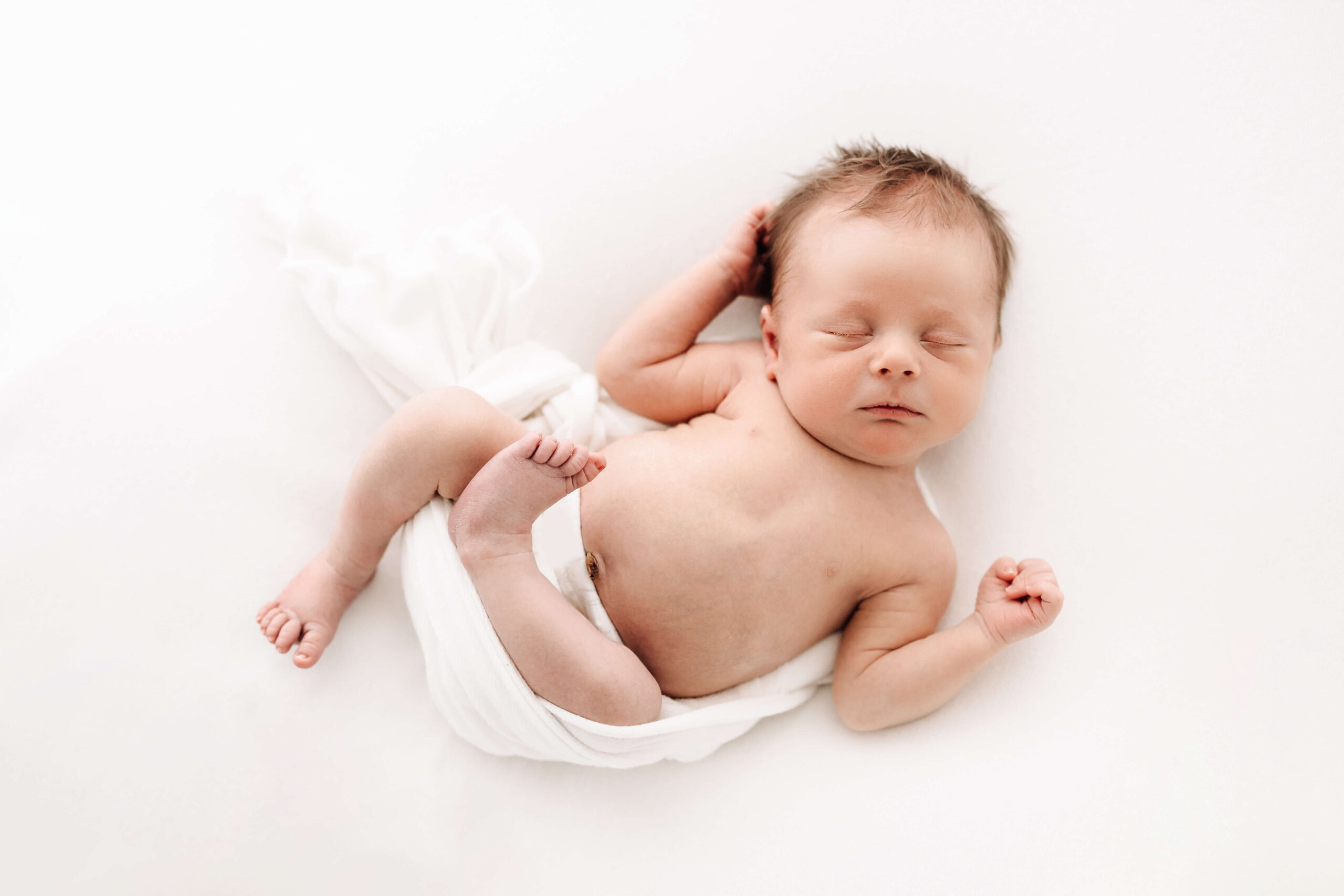 newborn baby boy in white swaddle