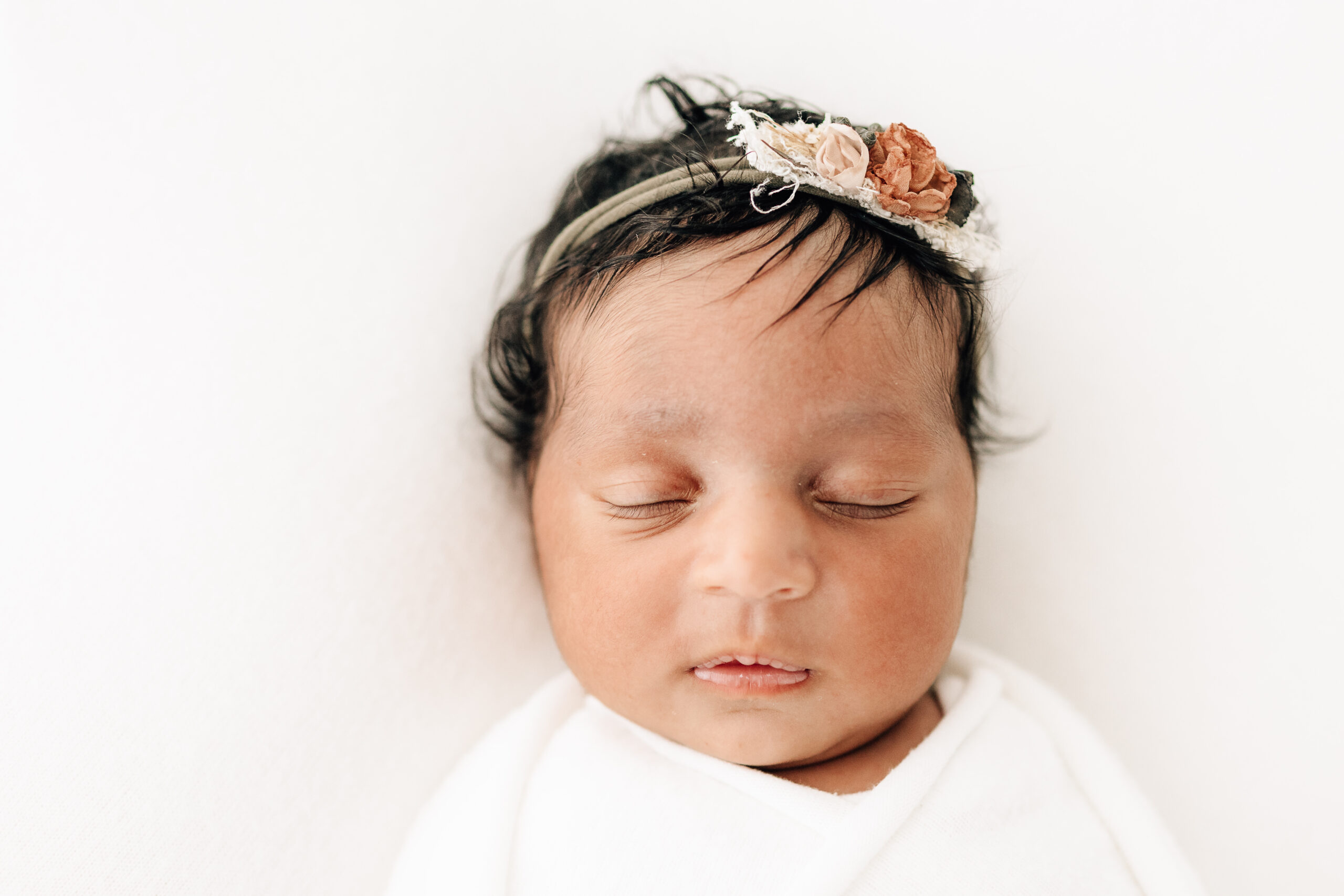 sleeping newborn baby on white backdrop