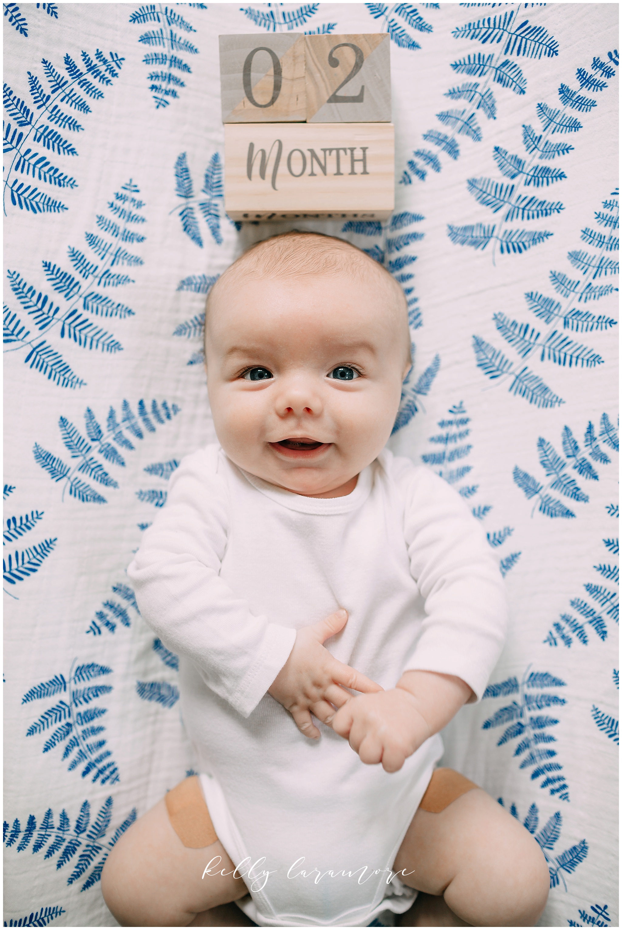 smiling newborn, blue and white blanket, monthly baby photos