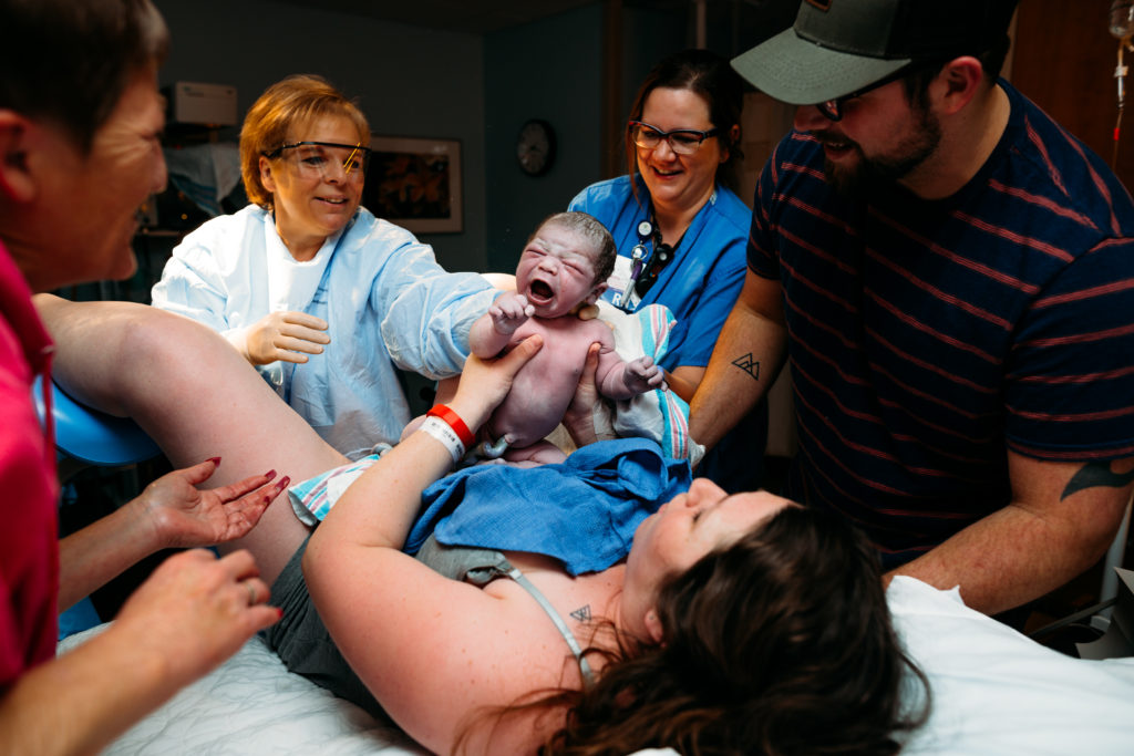 Newborn being held up by doctor moments after being born in labor room at Missouri Baptist Medical Center.