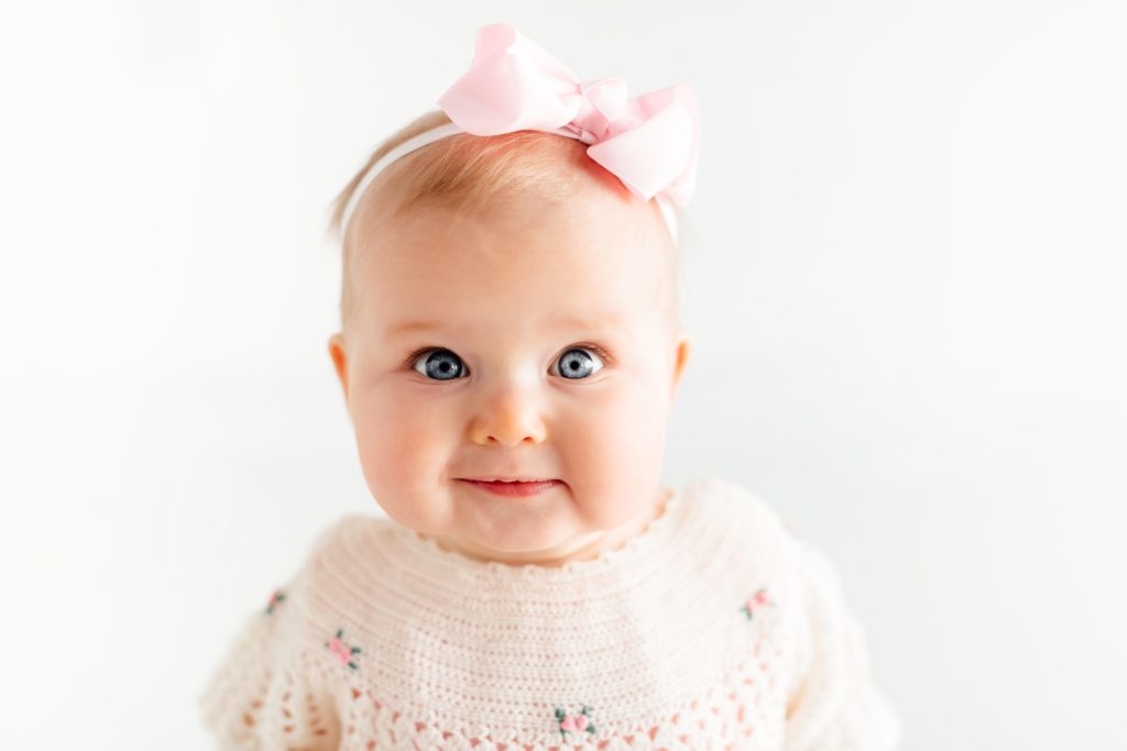 six month old with big blue eyes, wearing vintage dress for milestone session. 