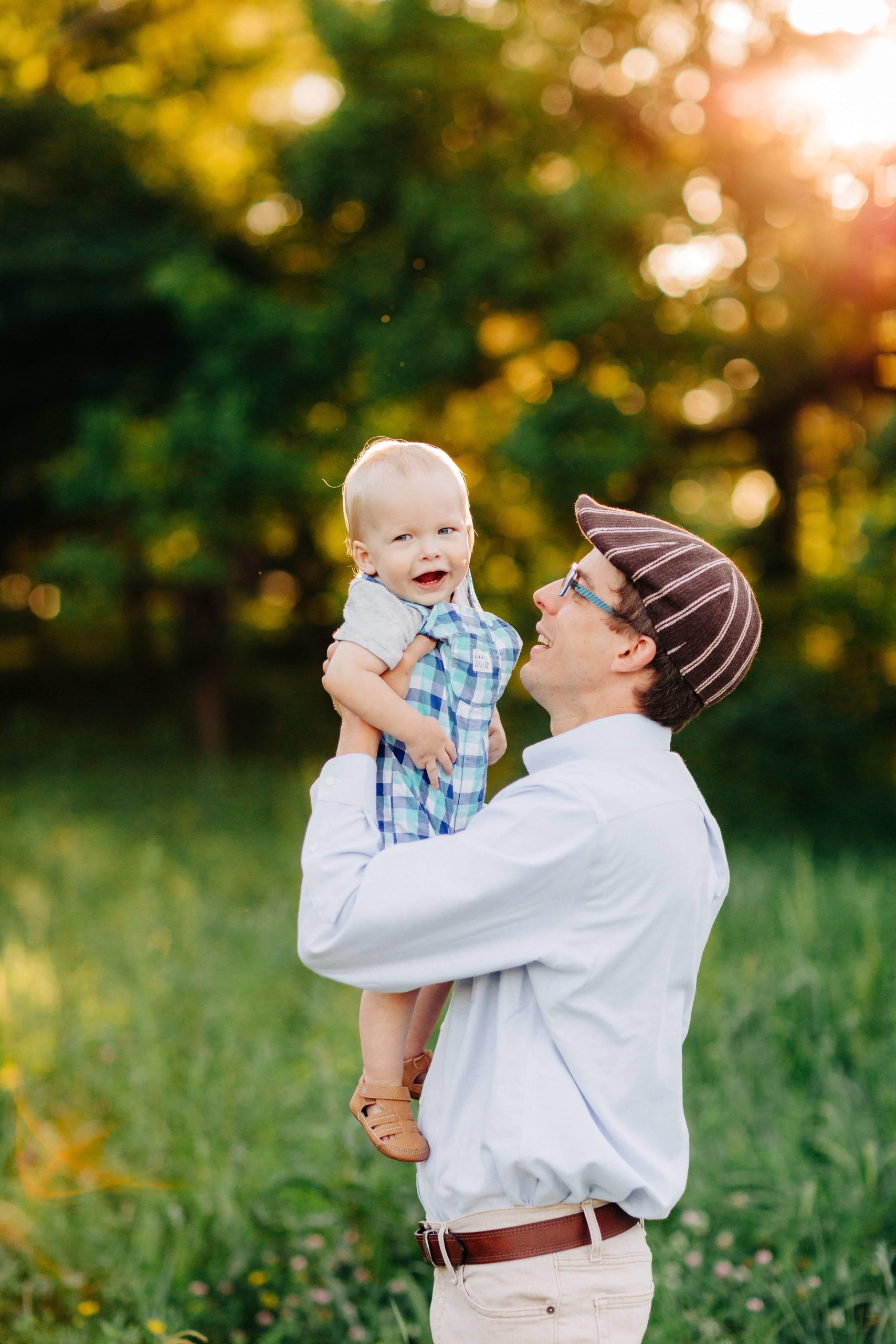 dad throwing baby in air, sunset first birthday session, smiling baby, baby in plaid