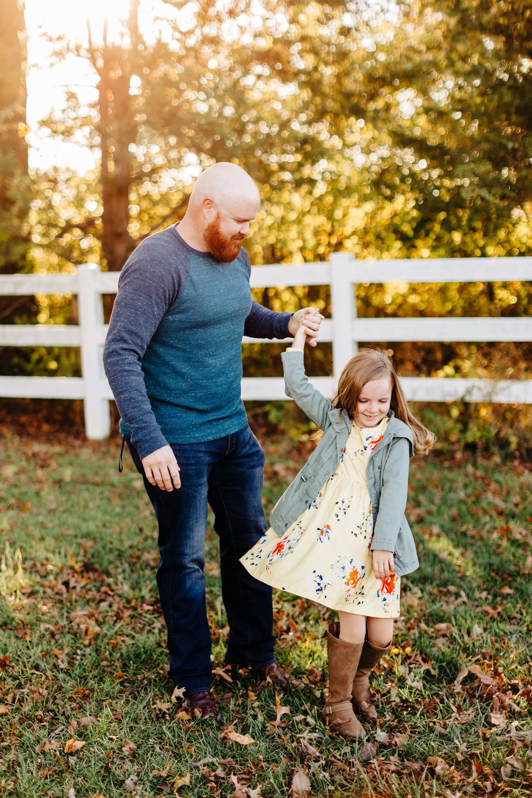 little girl spinning in dress with dad, white fence, fall family session at sunset, red beard, yellow flower dress, old navy jacket, fall boots