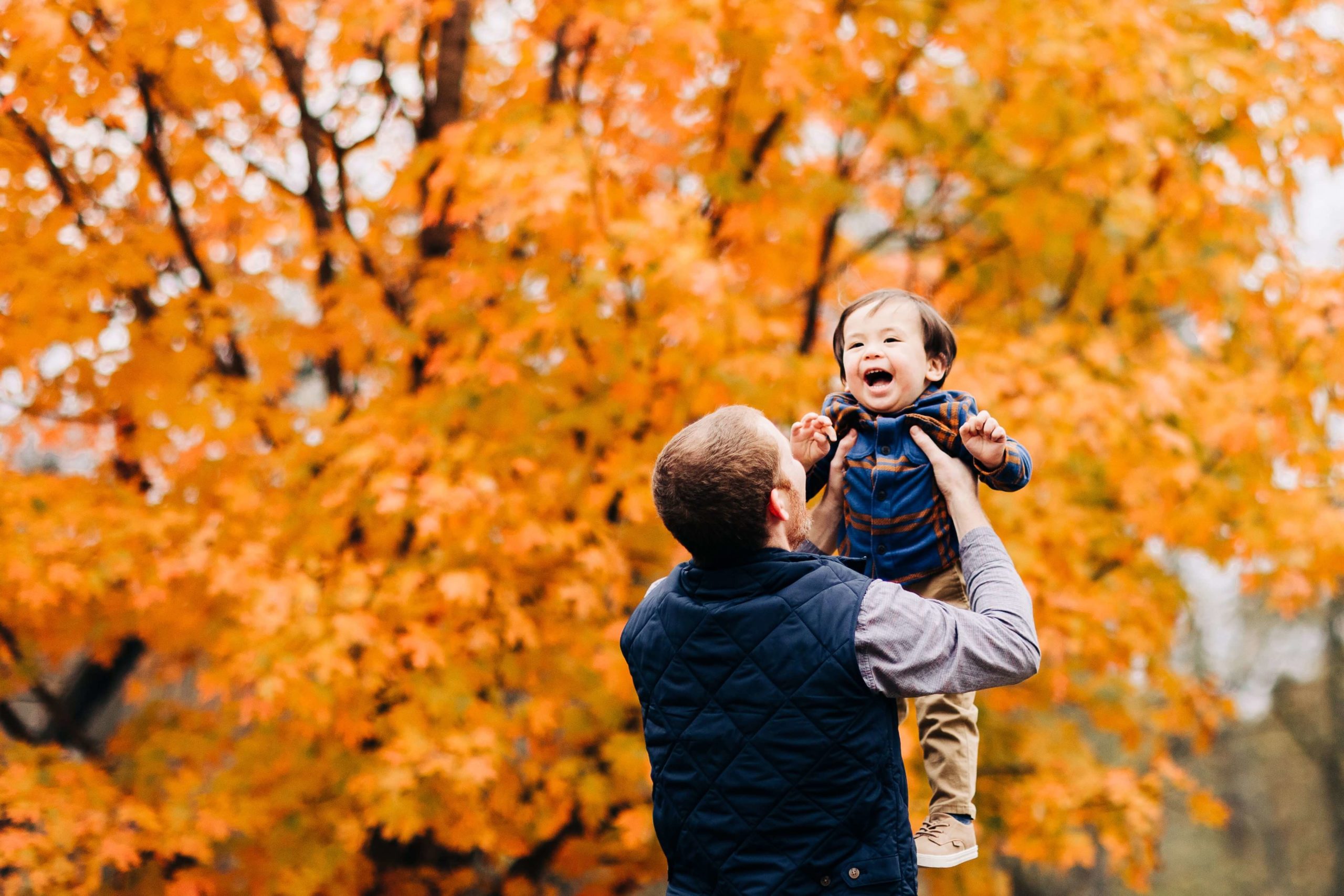 baby laughing, orange tree in the fall, dad lifting baby up