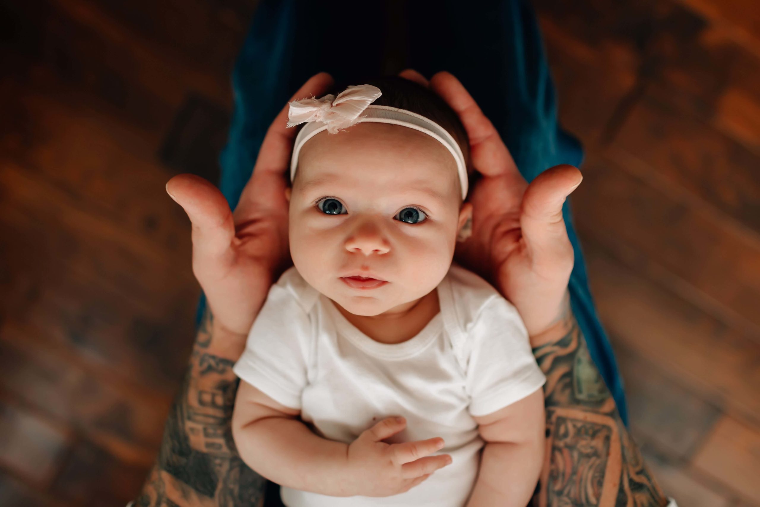 dad with arm tattoos holding newborn, newborn with pink bow