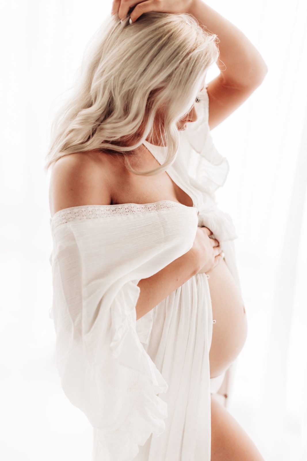 expecting mom in white free people dress holding belly. 