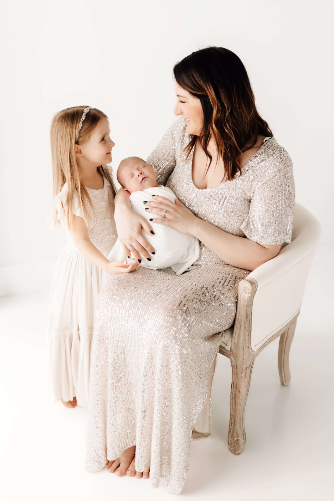 Mom, Big Sister, And baby Brother dressed in silver and white at St louis Photography Studio 
