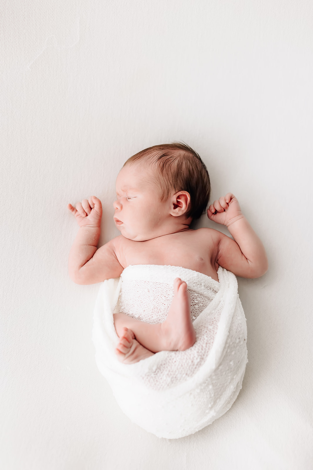 Newborn baby sleep in a white swaddle in a studio St Louis Doulas
