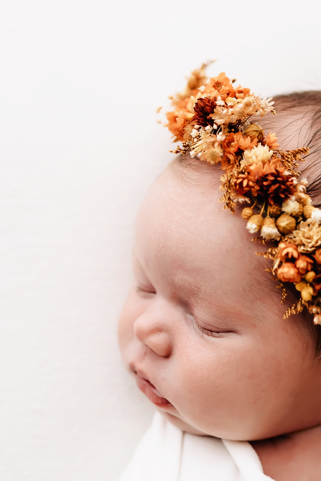 Details of a newborn baby sleeping in a floral headband Happy Up Inc