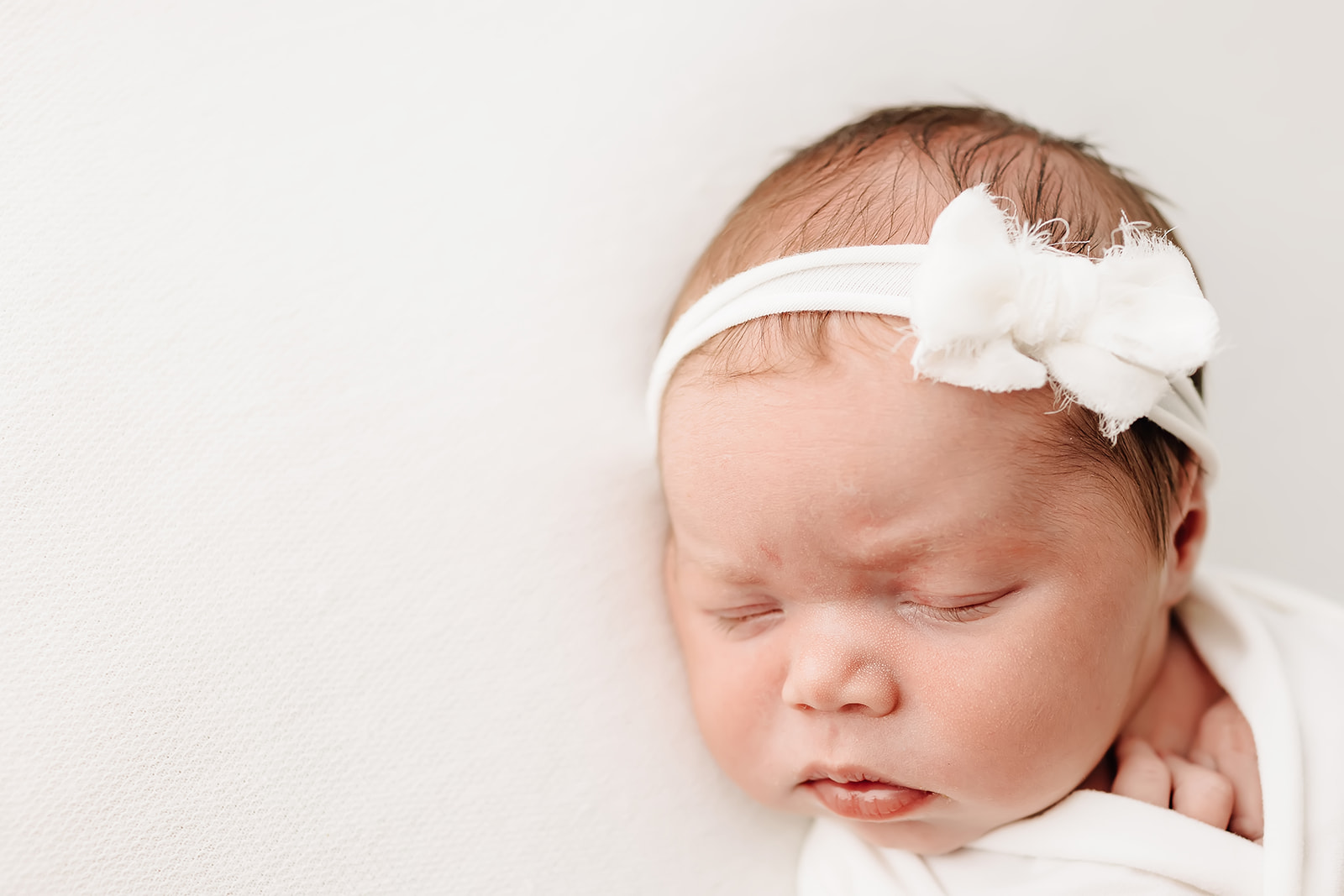 A newborn baby sleeps in a white bow Advanced OBGYN Services