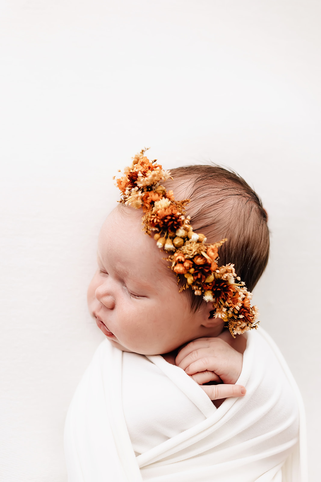 A newborn baby sleeps in a fall colored floral headband daycare st louis