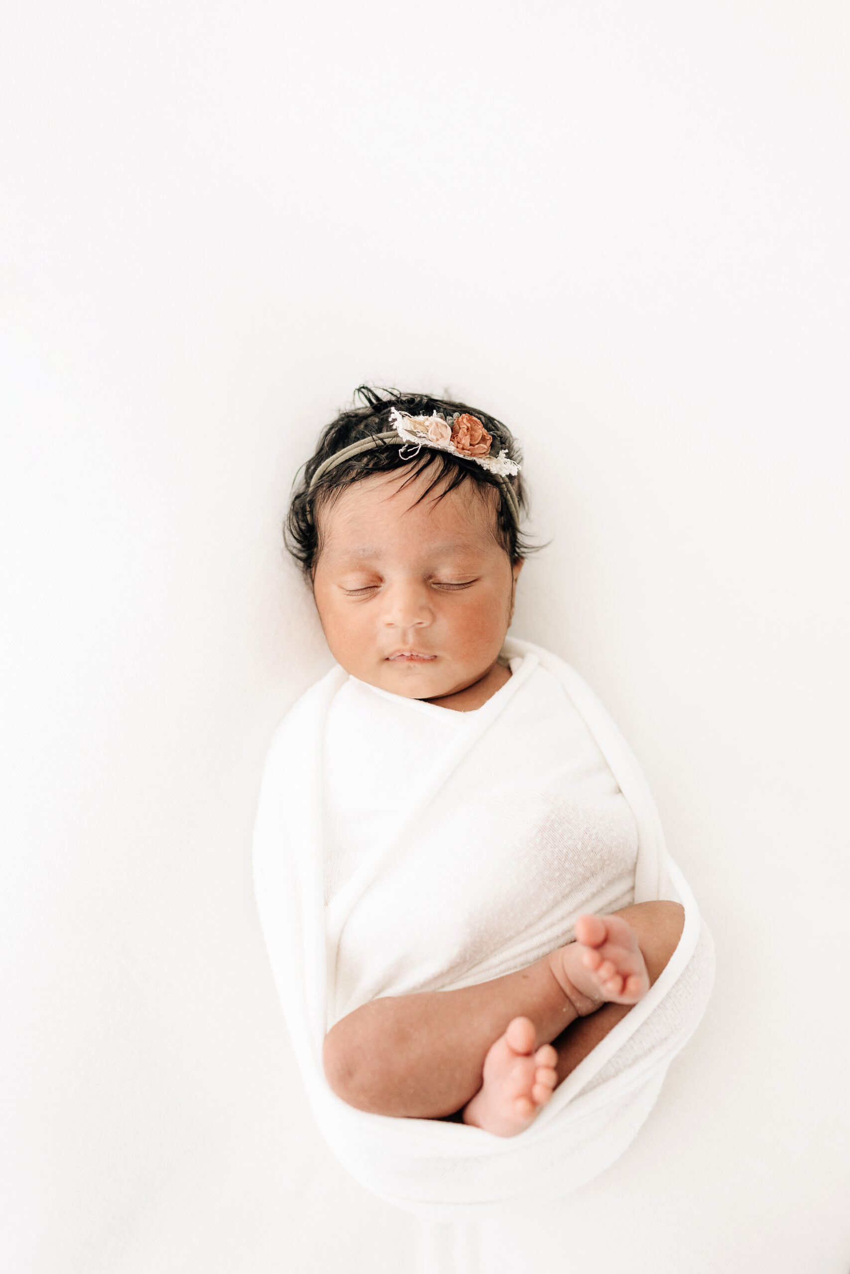 newborn baby girl swaddled in white
