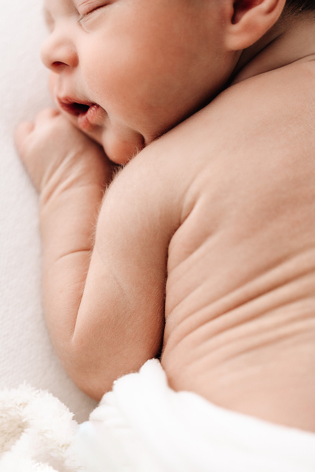 Details of a newborn baby sleeping with hairy arms