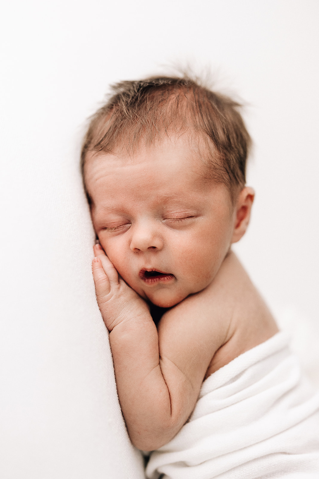 A newborn baby sleeps on its belly in a studio after some Baby music classes St. Louis