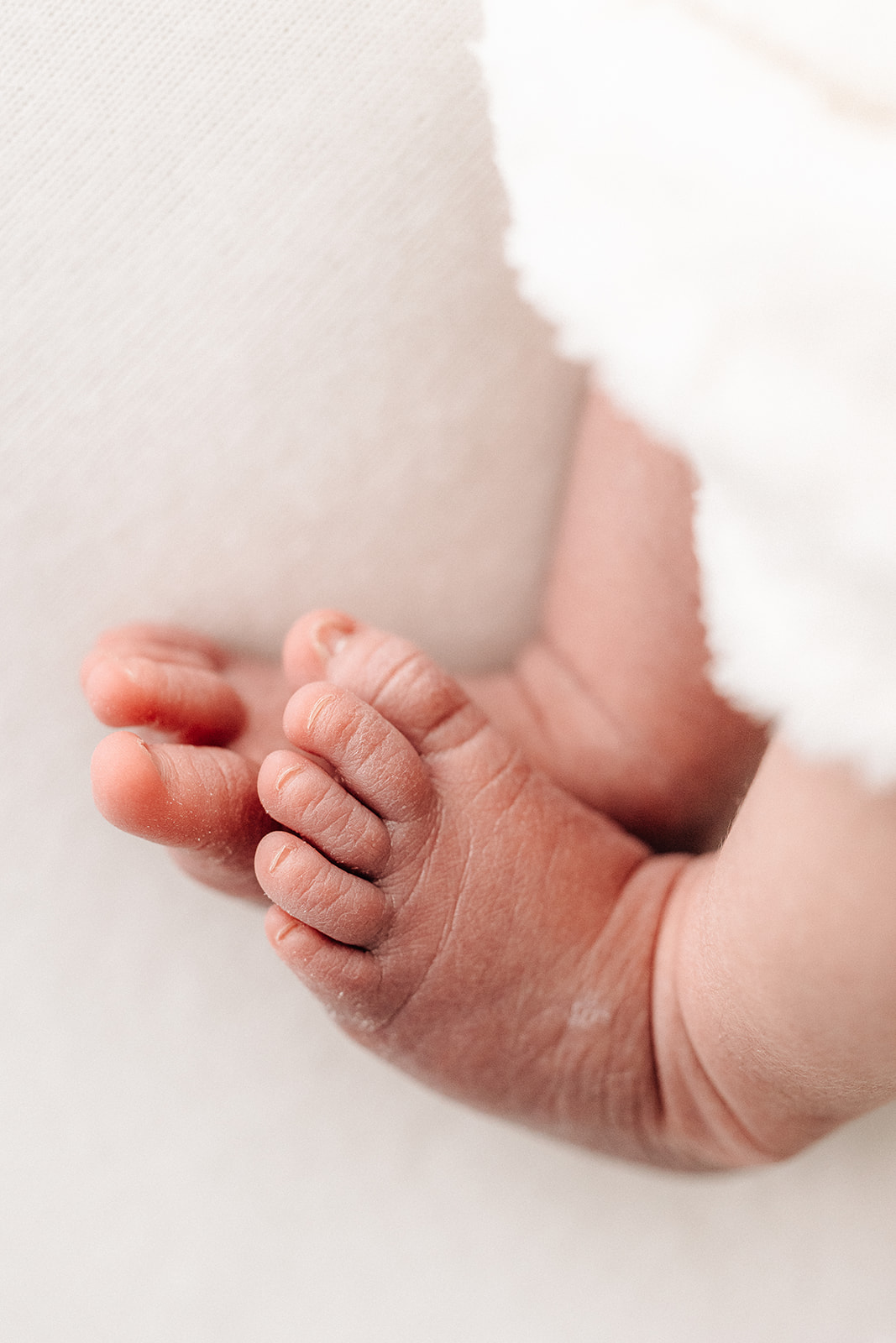 Details of a newborn baby's feet on a bed after meeting Tiny Transitions Sleep Consulting