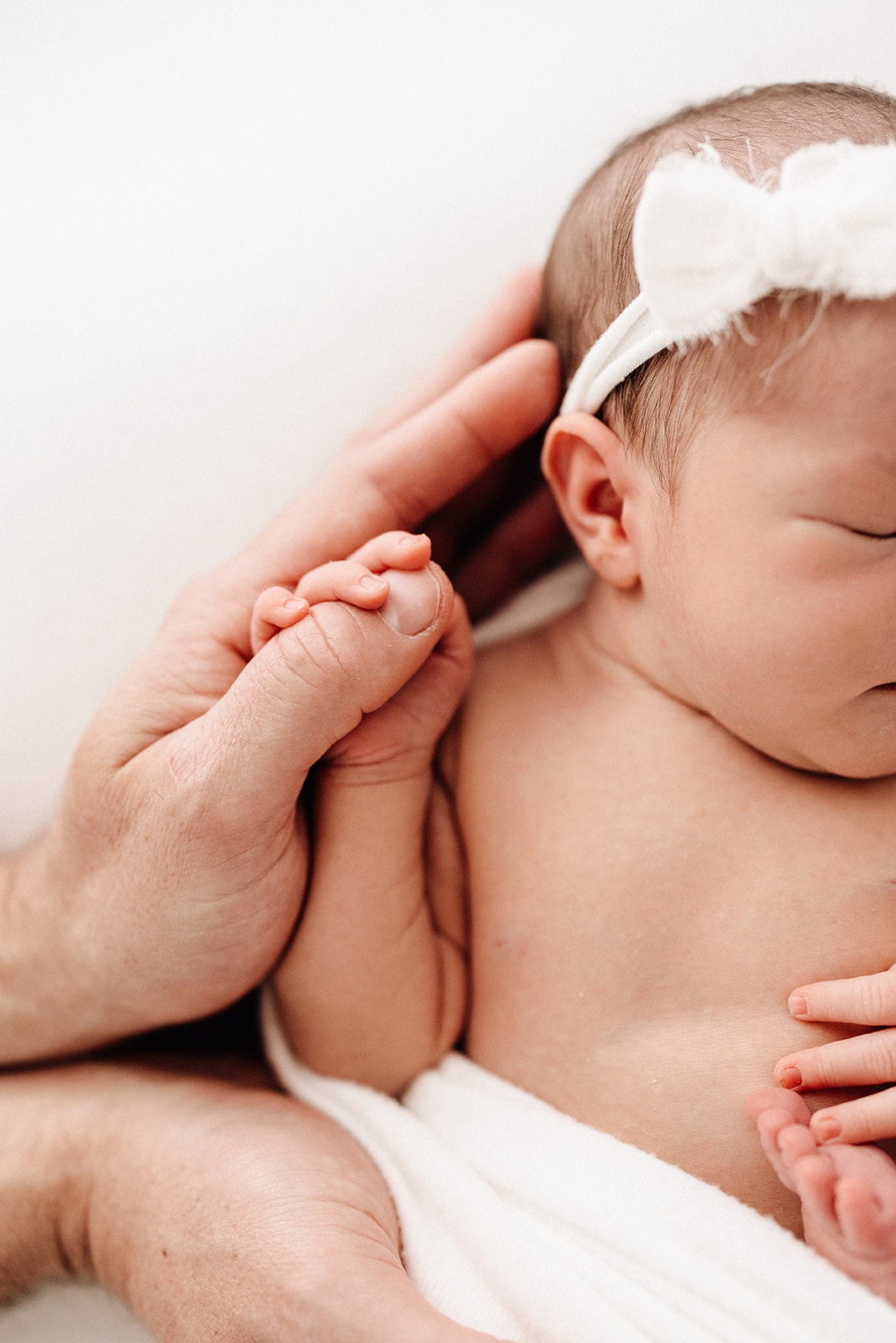 Details of a newborn baby holding dad's thumb while sleeping after visiting Moose Caboose